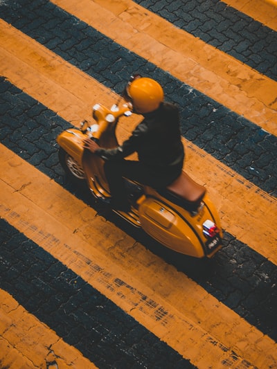 骑在黄色摩托车上的男人在黄色条纹线上
